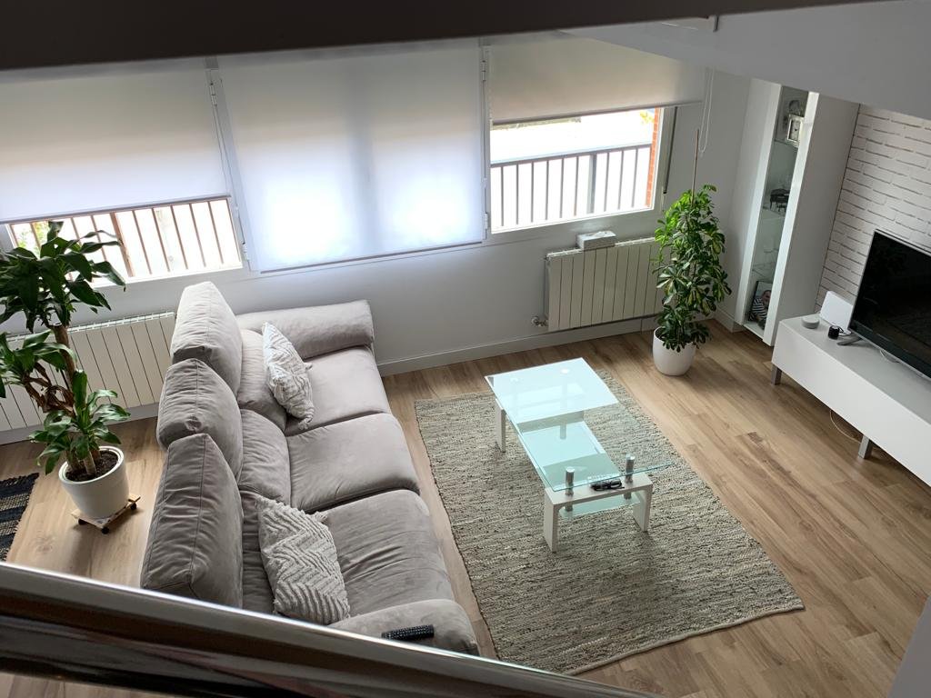 Salón reformado con vistas al balcón, suelo de tarima y decoración actual